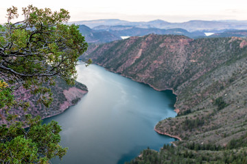 Tree framing view from Canyon Rim Campground in Flaming Gorge Utah National Park of Green River high angle aerial overlook in dark evening