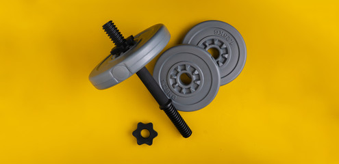 three gray plastic dumbbell pancakes on the color surface