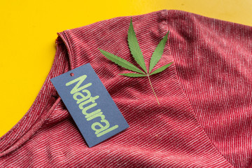 eco organic clothes made of the cannabis material on a color surface with a hemp leaf