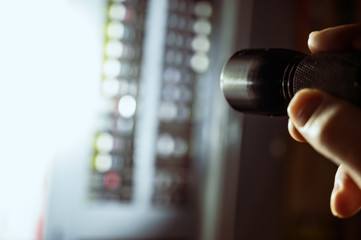 photo during a power outage with silhouette of hand holding a flashlight aimed at a fuse box