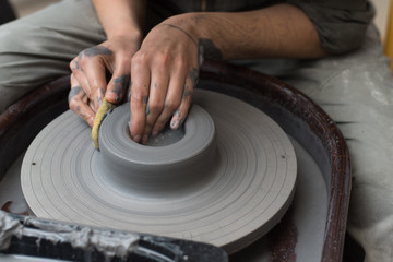 The master creates products from gray clay on a potter's wheel. Girl creates a ceramic vase