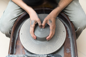 The master creates products from gray clay on a potter's wheel. Girl creates a ceramic vase