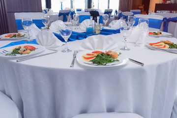 Tables and chairs in the restaurant with food and  full set preparation for dinner. Romantic dinner table setup.