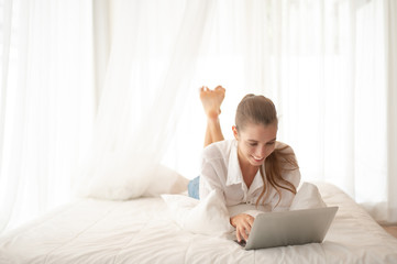 Girl relaxing holiday by listening to music on the bed. Girls working at home use laptops and the Internet.
