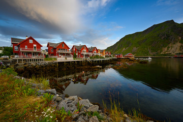 Fototapeta na wymiar Beautiful waterfront house reflecting the water Evening and twilight sky at ballstad city, lofoten island in northern Norway. Rorbuer is the traditional home of Norwegian fishermen.