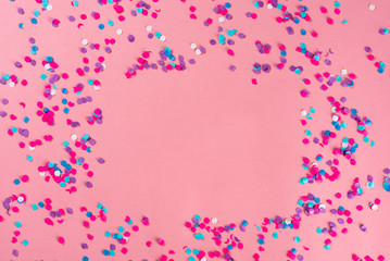 Festive party holiday colorful confetti on pink pastel background with copy space.