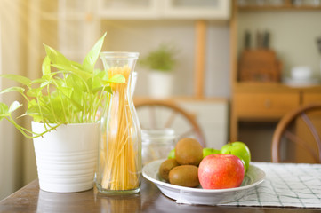 There are fruit plates, spaghetti and vases on the breakfast table.