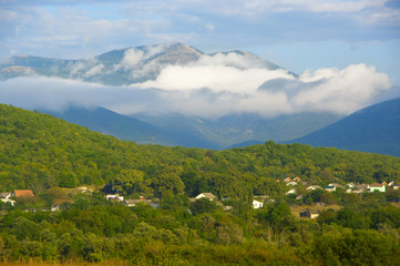 Fototapeta na wymiar Sunny valley among foggy mountains