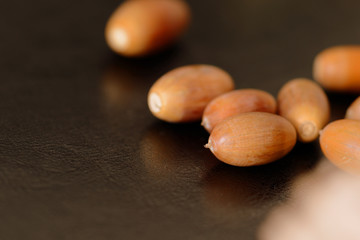 Acorns and dry oak leaves on a dark surface close up. Autumn background