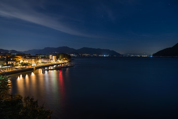 Obraz premium Famous big European lake at night. Lake Maggiore with the city of Maccagno, in the background the lights of the stretch of coast between the cities of Germignaga and Stresa, Italy
