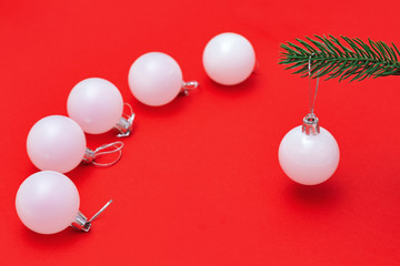 Christmas decoration, beautiful white ball close up on fir tree branch over red background with copy space. New Year and winter Holiday concept.