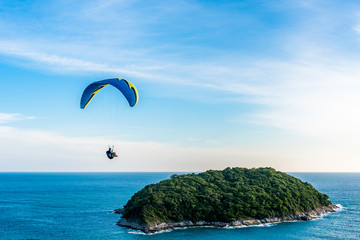 Paragliding Extreme sport, Paraglider flying on the blue sky and white cloud in Summer day at Phuket Sea, Thailand.