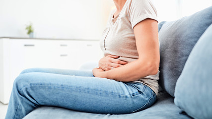 Woman with  stomach issues / problems while sitting on the couch.