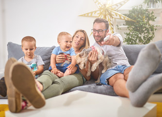 Young parents watching TV with baby boy and a dog.