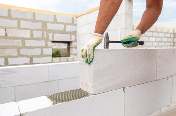 A worker lays foam concrete bricks in a house under construction