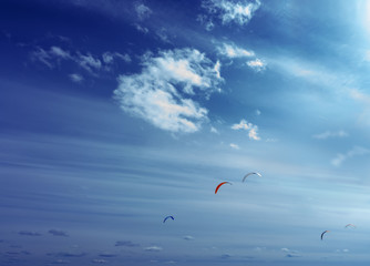Colorful kites flying in a blue sky with air clouds.