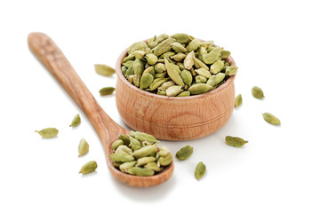 Cardamom pods in a wooden bowl isolated on white background.