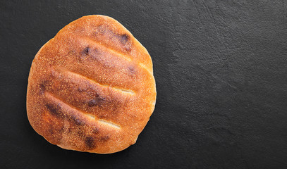 Fresh hot focaccia bread (pita) on black stone background.