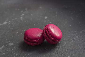 Colorful french macarons cookies(macaroons) on a dark background with copy space. Dessert for served with tea or coffee break.