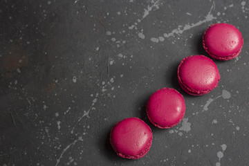 Colorful french macarons cookies(macaroons) on a dark background with copy space. Dessert for served with tea or coffee break.