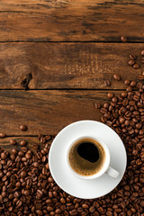 Coffee cup with beans on vintage wooden table with copyspace. Top view