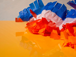 Red, white and blue paper garlands on an orange table for the Dutch Kings day. Room for text.