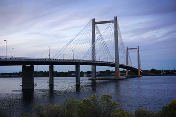 Cable-stayed bridge over river at sunset