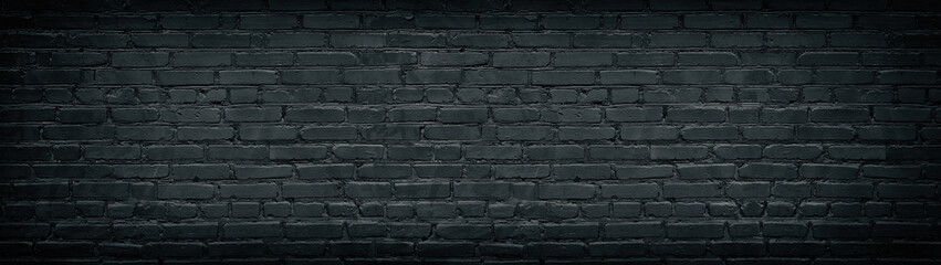 Widescreen black brick wall texture. Aged rough masonry background. Dark brickwork wide back...