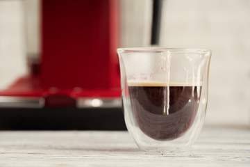 Glass cup of coffee at kitchen counter close up