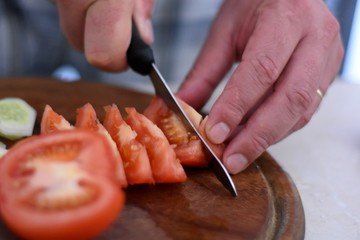 Obraz premium Closeup of hands of chef cook cutting vegetables on wooden table