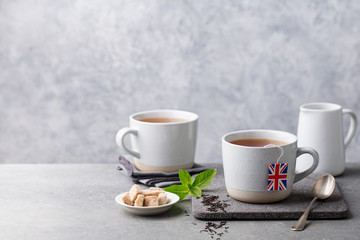 Tea in mugs with British flag tea bag label. Grey background. Copy space.