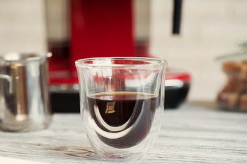 Glass cup of coffee at kitchen counter close up