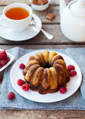 Chocolate marble bundt cake with a cup of tea on wooden background.
