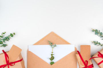 Christmas gift with red bow and greeting card on white wooden background