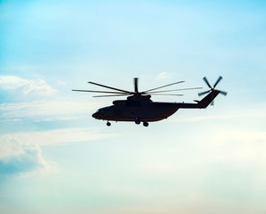 Naklejka na ściany i meble Silhouette of heavy transport helicopter flying against the blue sky