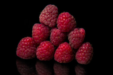 berries of red raspberries in a bunch lie on a black glass top view. sweet summer berries