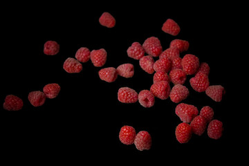 berries of red raspberries in a bunch lie isolated on a black background top view. sweet summer berries