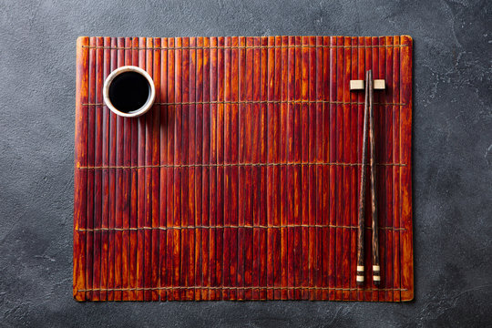 Asian table place setting with bamboo placemat, sauce bowl and chopsticks. Top view. Copy space.