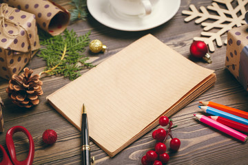 Writing christmas greeting cards. Open notepad with pen on decorated wooden table