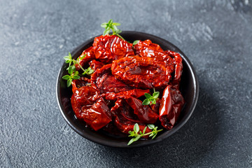 Sun dried tomatoes with fresh herbs and spices. Slate background. Top view. Close up.