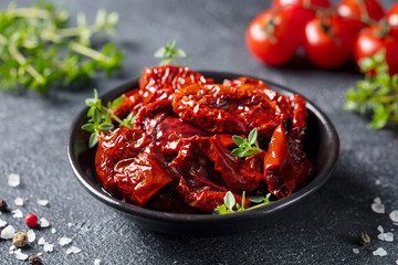 Sun dried tomatoes with fresh herbs and spices. Slate background. Close up.