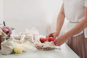 Women's hands and net bags with apples