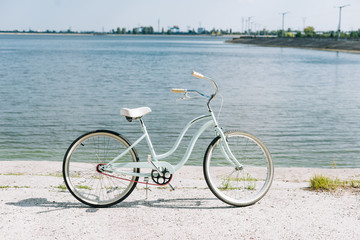 Fototapeta premium side view of bicycle near blue river in summer in sunshine