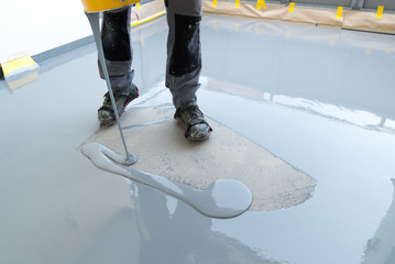 construction worker renovates balcony floor and pours watertight resin and glue before chipping and sealing - obrazy, fototapety, plakaty