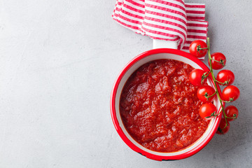 Traditional tomato sauce in saucepan. Grey background. Top view. Copy space.