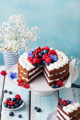 Chocolate cake with whipped cream and fresh berries. Blue wooden background. Copy space.