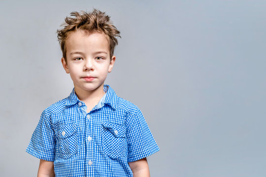 Cute Boy In A Blue Shirt On A Gray Background.