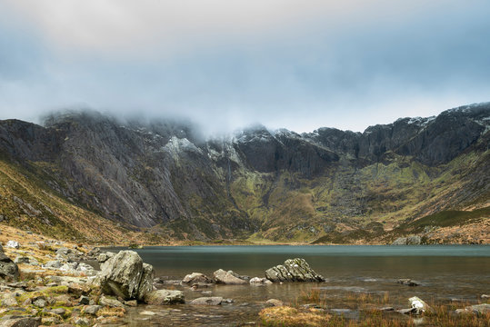 Beautiful moody Winter landscape image of Llyn Idwal and snowcapped Glyders Mountain Range in Snowdonia