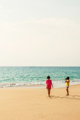 Two girls relaxing on the beach with digital camera.