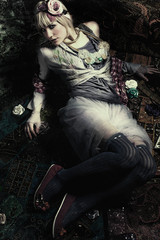 beautiful young blond woman in  colorful boho style  clothes lie in dark room on floor shot from above